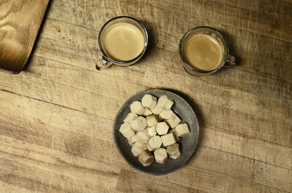 Close up view of bicycle gears resting next to a fresh cup of coffee on a wooden workbench