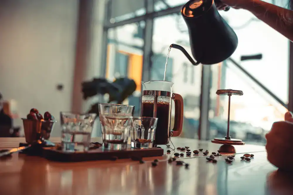 A barista pouring coffee in the foreground with a mechanic tuning a bicycle in the background